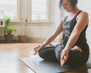 Yoga Teacher Katie thorne sitting on yoga mat in yoga studio