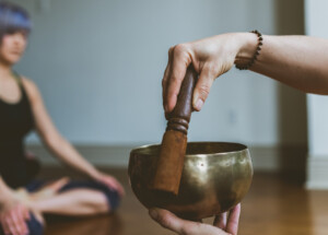 hand holding mallet for siging bowl during yoga mantra